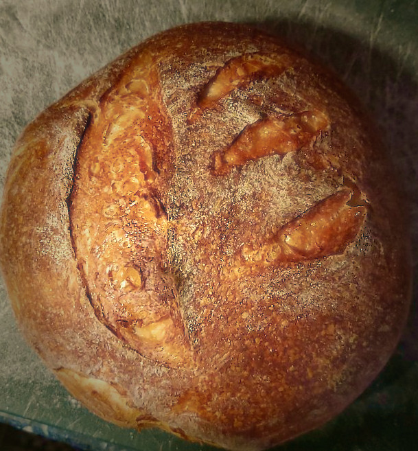 A loaf of sourdough bread on a green cutting board